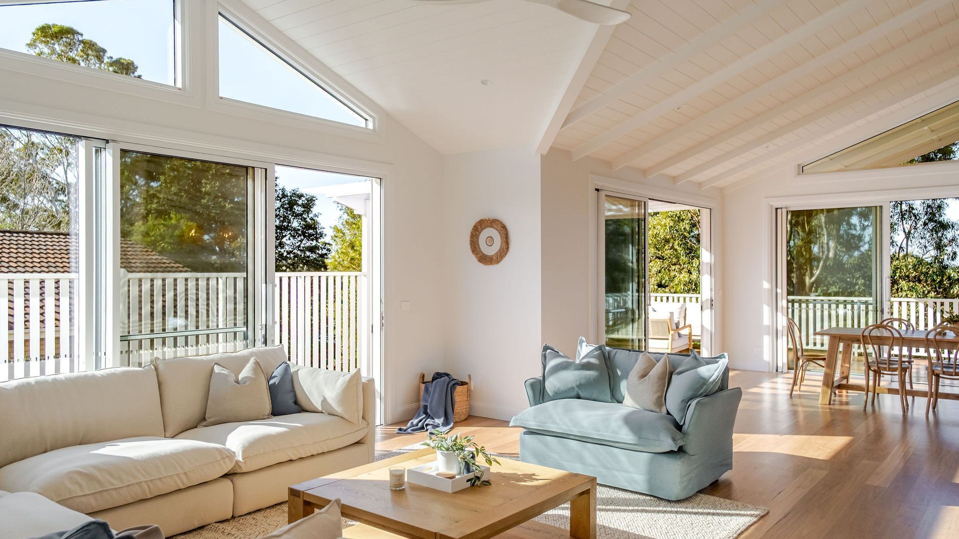A spacious living area with a large window, a sofa, a coffee table, and a dining area with chairs.