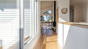 A modern interior with a wooden floor, a dining area with chairs, and a kitchen area with a counter. - Molly-a-la-Plage - Beautiful, spacious and modern beach house in Mollymook Beach (Mollymook Beach)