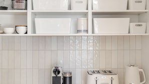 A kitchen with white cabinets, a toaster, a kettle, and a coffee maker. - Molly-a-la-Plage - Beautiful, spacious and modern beach house in Mollymook Beach (Mollymook Beach)