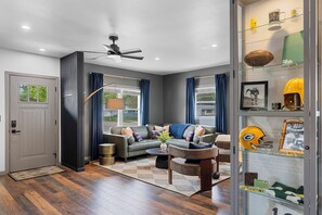 Ein modernes Wohnzimmer mit einer Couch, einem Couchtisch und einer Vitrine mit Sportmemorabilien.