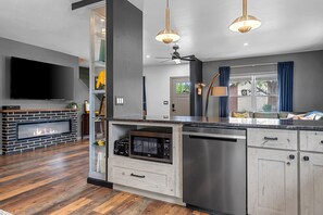 Una cocina moderna con lavavajillas integrado, televisor de pantalla plana y chimenea.