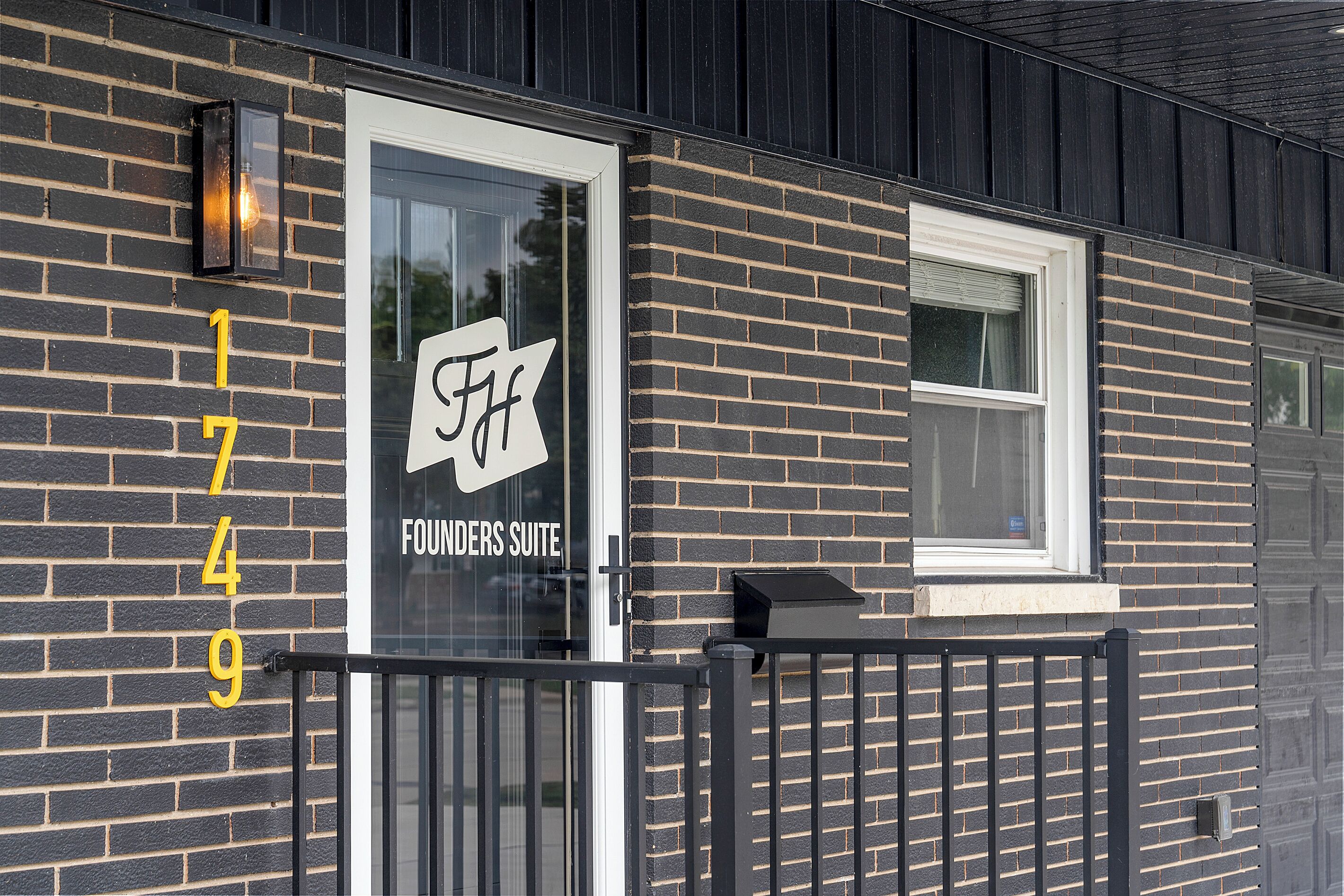 A building with a glass door labeled 'Founders Suite' and a black metal fence.