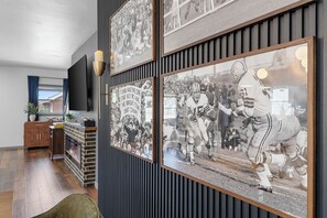 A room with a fireplace, a television mounted on the wall, and framed sports memorabilia on the wall.