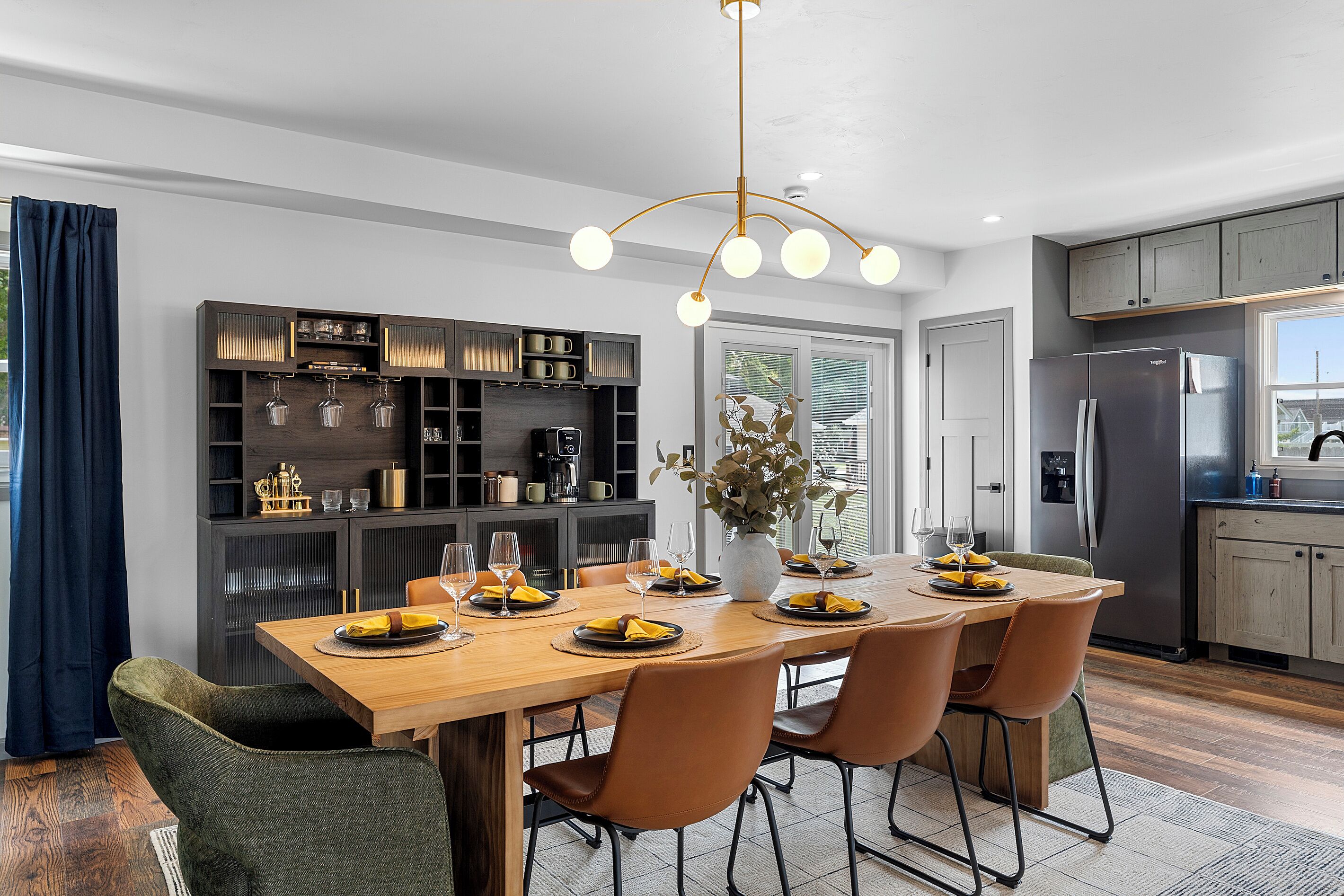 A modern kitchen with a central island, built-in cabinets, and a dining area with chairs and a table set for a meal.