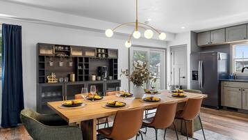 A modern kitchen with a central island, built-in cabinets, and a dining area with chairs and a table set for a meal.