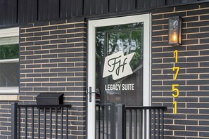 Een gevel met glazen deur, een bord waarop 'FF Legacy Suite' staat en het cijfer '1751' in het geel op de muur.