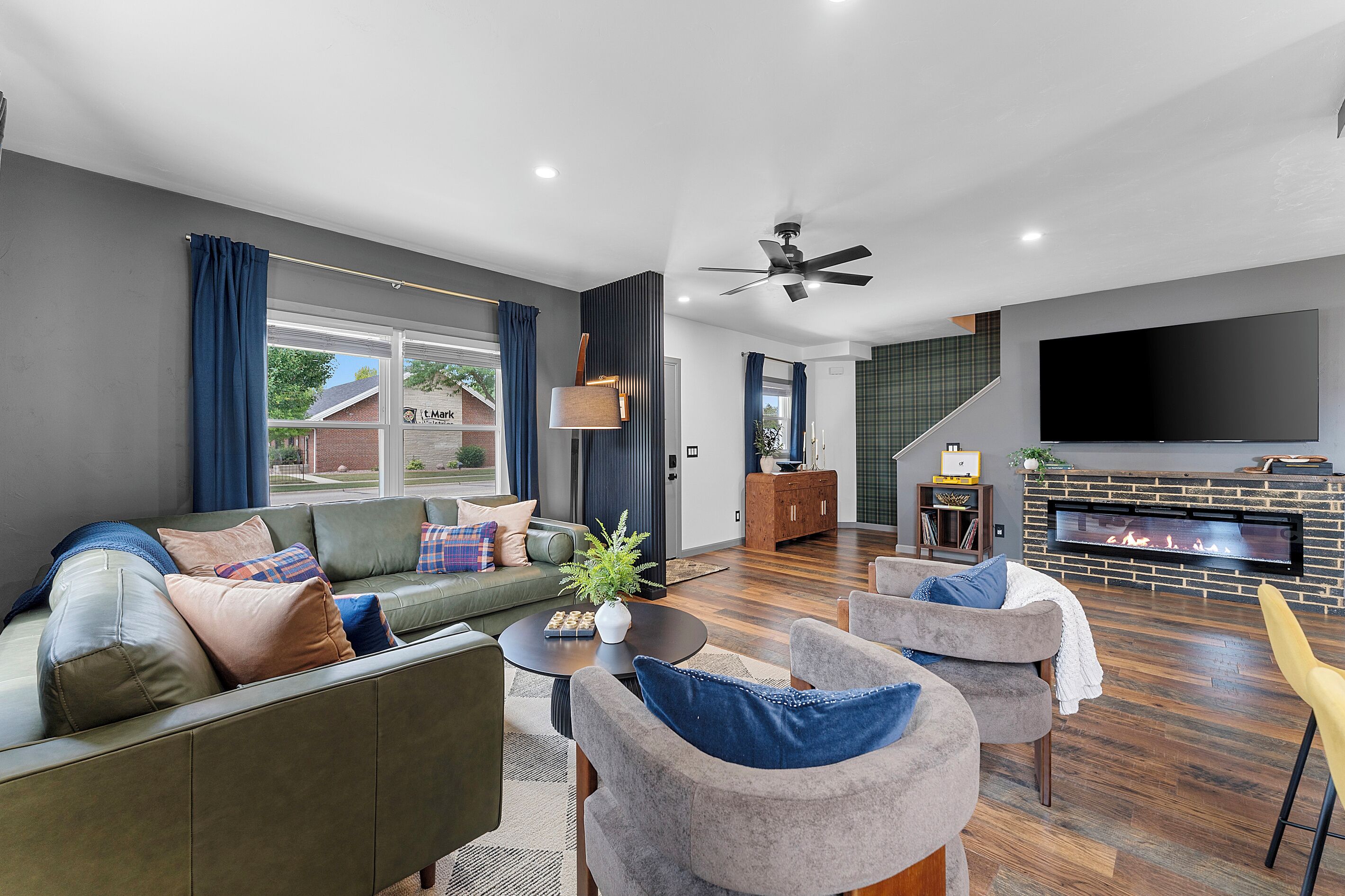 Een moderne woonkamer met een bank, stoelen, een bijzettafeltje en een open haard.