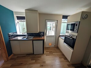 A compact kitchen with a sink, a coffee maker, and a microwave. - Apartment Sleeps 4 - Town Centre & Near Beach (Newquay)