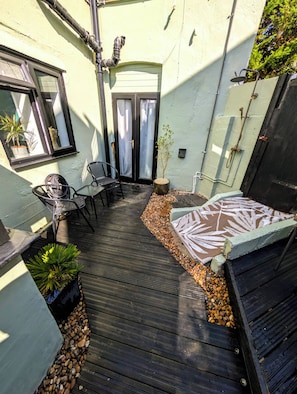 A covered outdoor seating area with a table and chairs, a potted plant, and a patterned rug. - Apartment Sleeps 4 - Town Centre & Near Beach (Newquay)