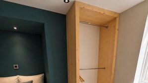 Makuuhuone, jossa on sänky, puinen vaatekaappi, tuoli ja ikkuna.