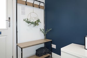 A room with a white door, a wooden shelf, a small table, a dark-colored cat, and a wall with a dark blue paint. - Cosy One-Bedroom in Birchgrove, Cardiff (Cardiff)
