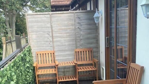 Um deck de madeira com assentos e uma grade de metal.