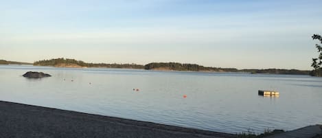 A calm lake with a wooden dock extending into the water, surrounded by a forested shoreline.