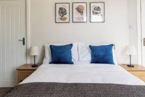 A bedroom with a bed, two bedside tables, and three framed artworks on the wall. - 3 Br home perfect for big groups (Darlington)