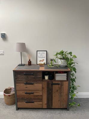 Ein Holztisch mit Schubladen, einer Lampe, einem gerahmten Zitat und einem Blumentopf.