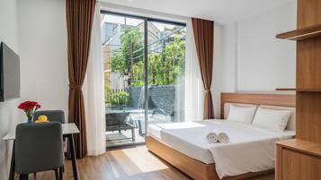 A modern hotel room with a bed, a desk, and a view of a courtyard.