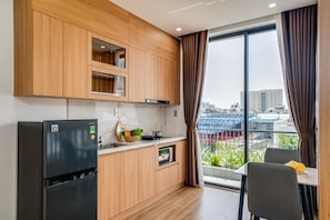 Cozinha moderna com armários de madeira, uma geladeira preta e um espaço de jantar com mesa e cadeiras.