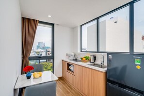 Una cocina compacta con refrigerador, lavamanos y una ventana con cortinas.