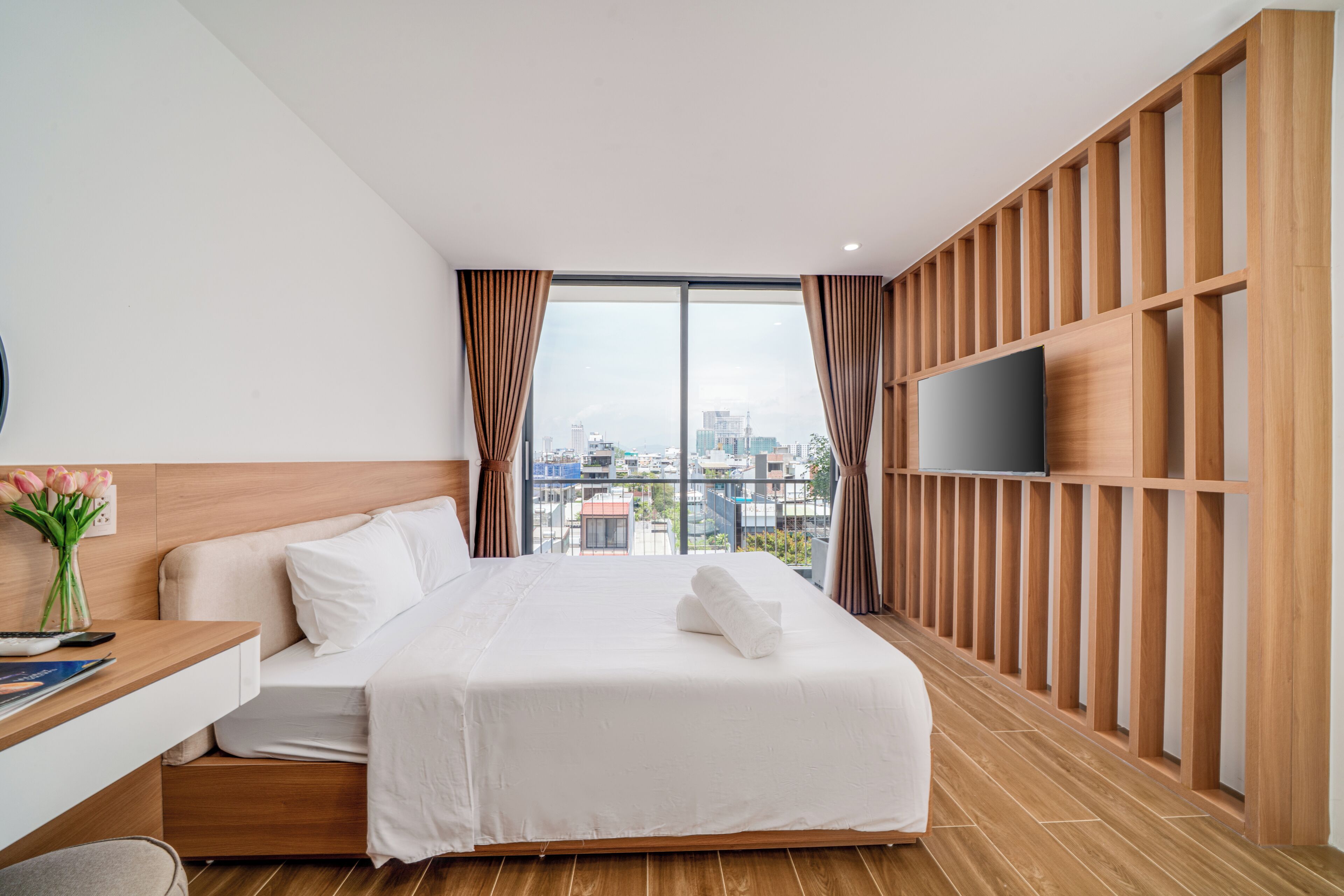 Una habitación de hotel con una cama, un escritorio, un televisor y vistas a la ciudad.