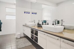 Um banheiro moderno com duas pias, um espelho grande e piso em azulejos.