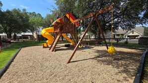 Ein Spielplatz mit Rutsche, Schaukeln und einer Kletterkonstruktion.
