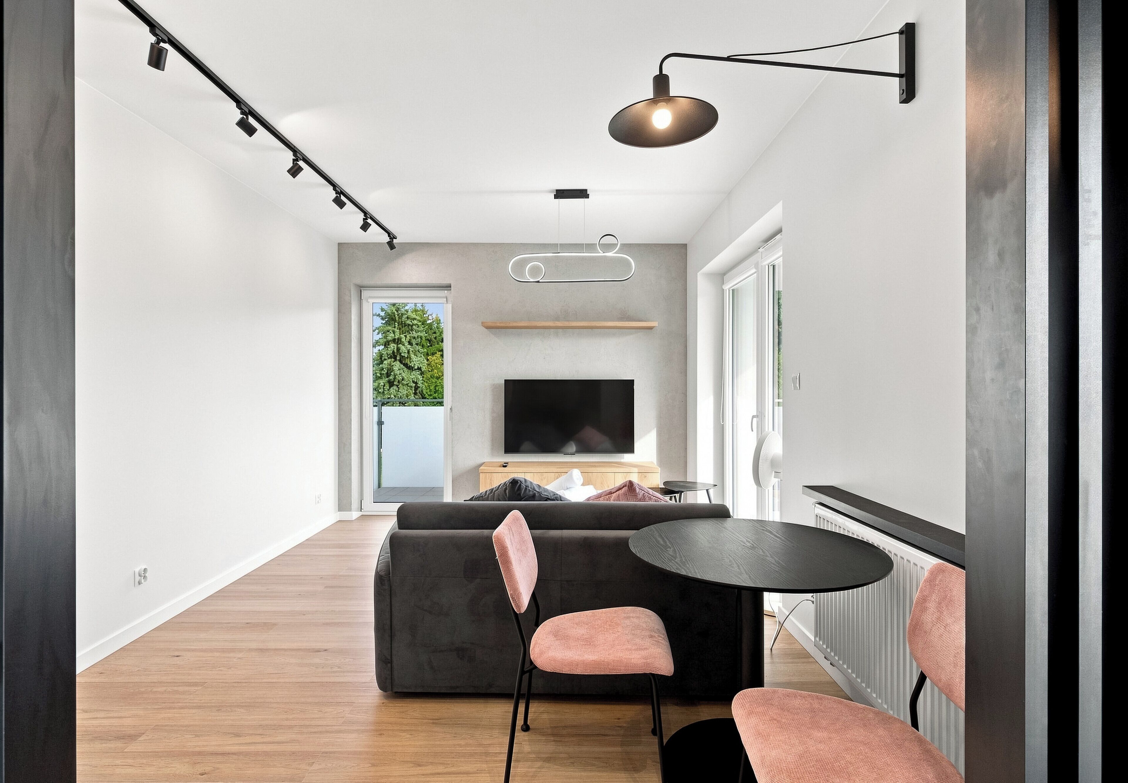 Un salon moderne avec un canapé, des fauteuils, un téléviseur et une table à manger.