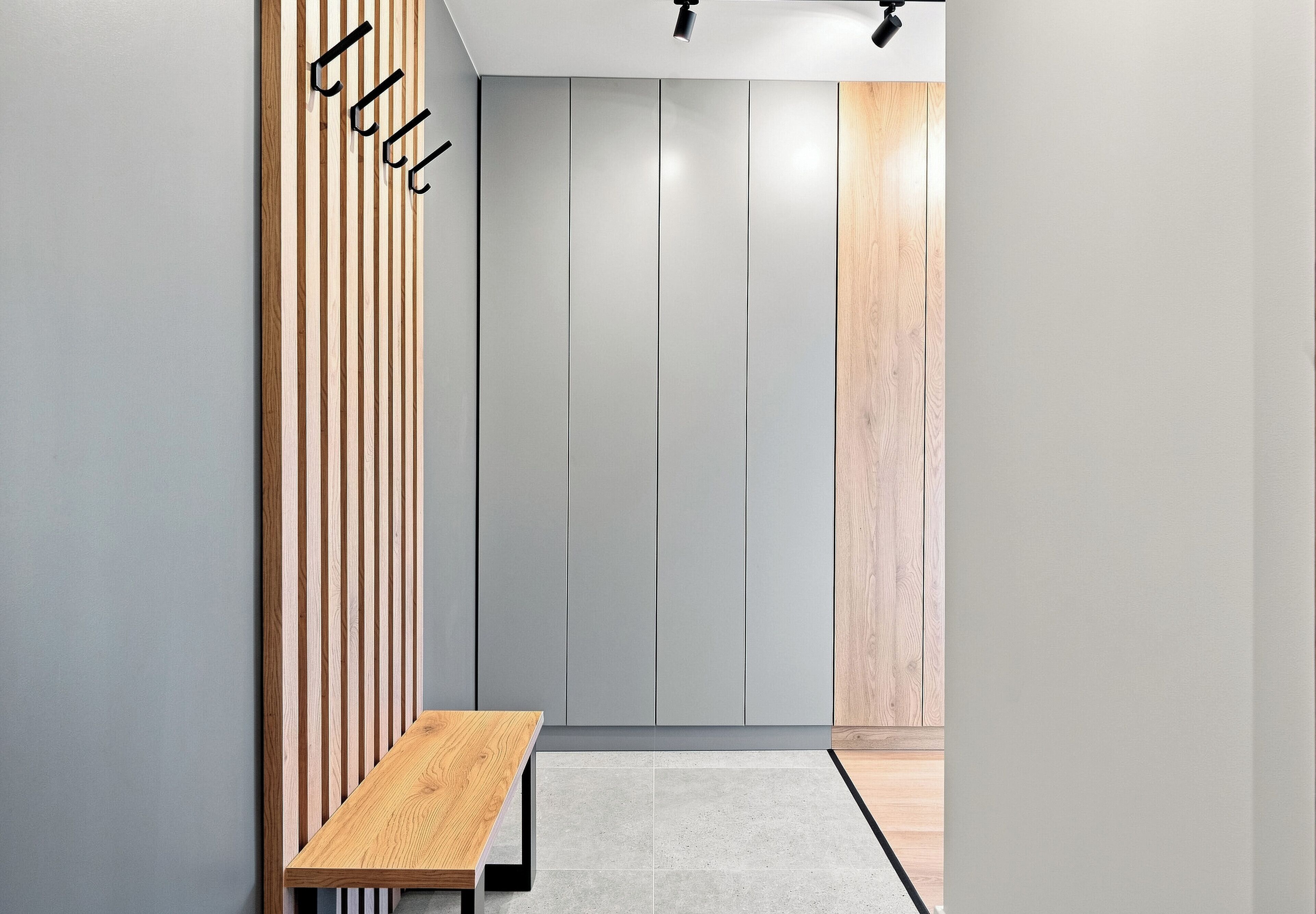 A hallway with a bench, vertical wooden slats, grey walls, and a door with a wooden panel.