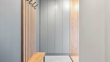 A hallway with a bench, vertical wooden slats, grey walls, and a door with a wooden panel.
