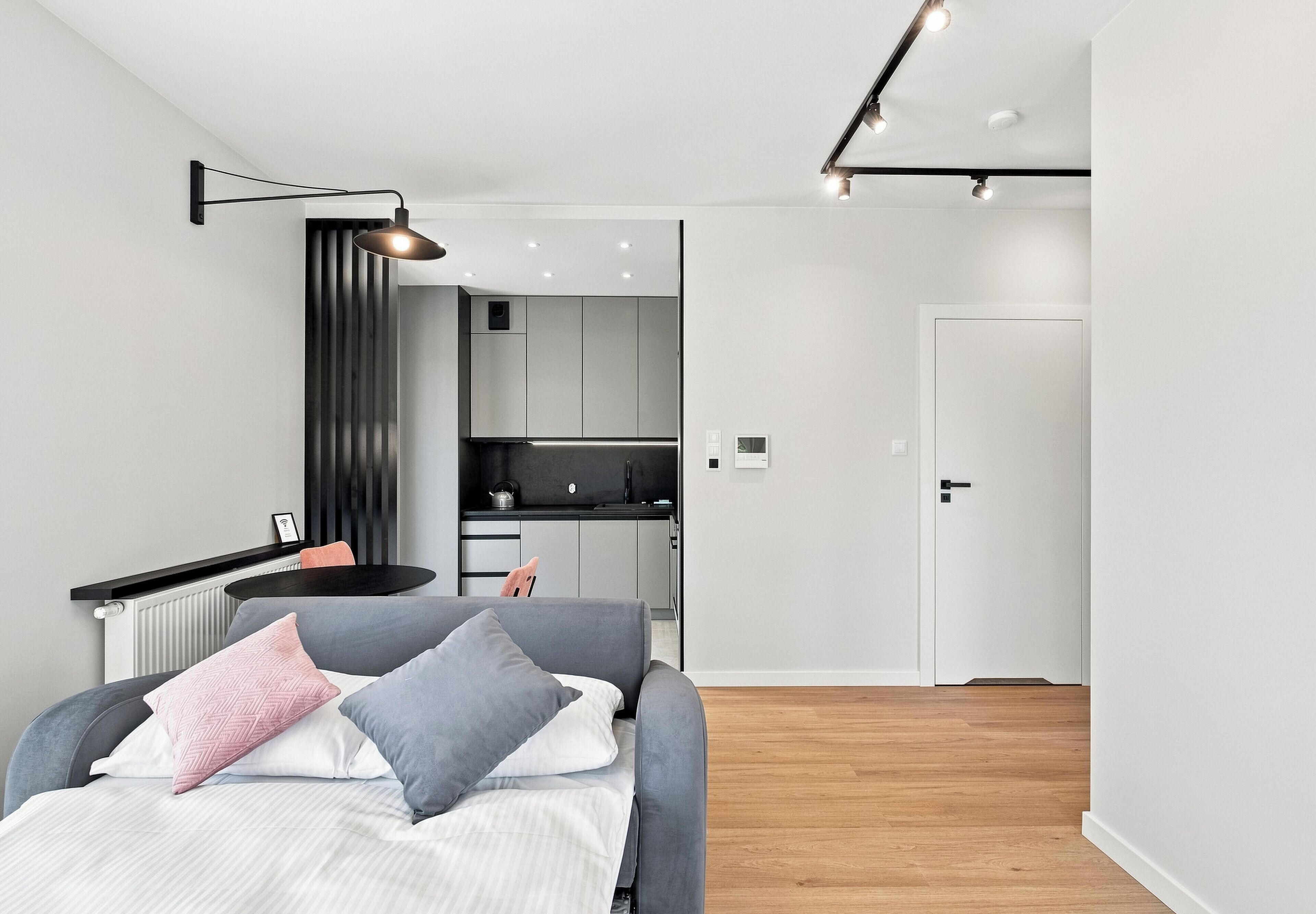 Ein modernes Schlafzimmer mit Bett, Nachttisch und Blick in den angrenzenden Küchenbereich.