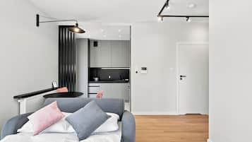 Ein modernes Schlafzimmer mit Bett, Nachttisch und Blick in den angrenzenden Küchenbereich.