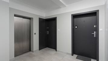 A hallway with three doors, each with a handle and a lock. The floor is tiled, and the walls are painted in a light color.