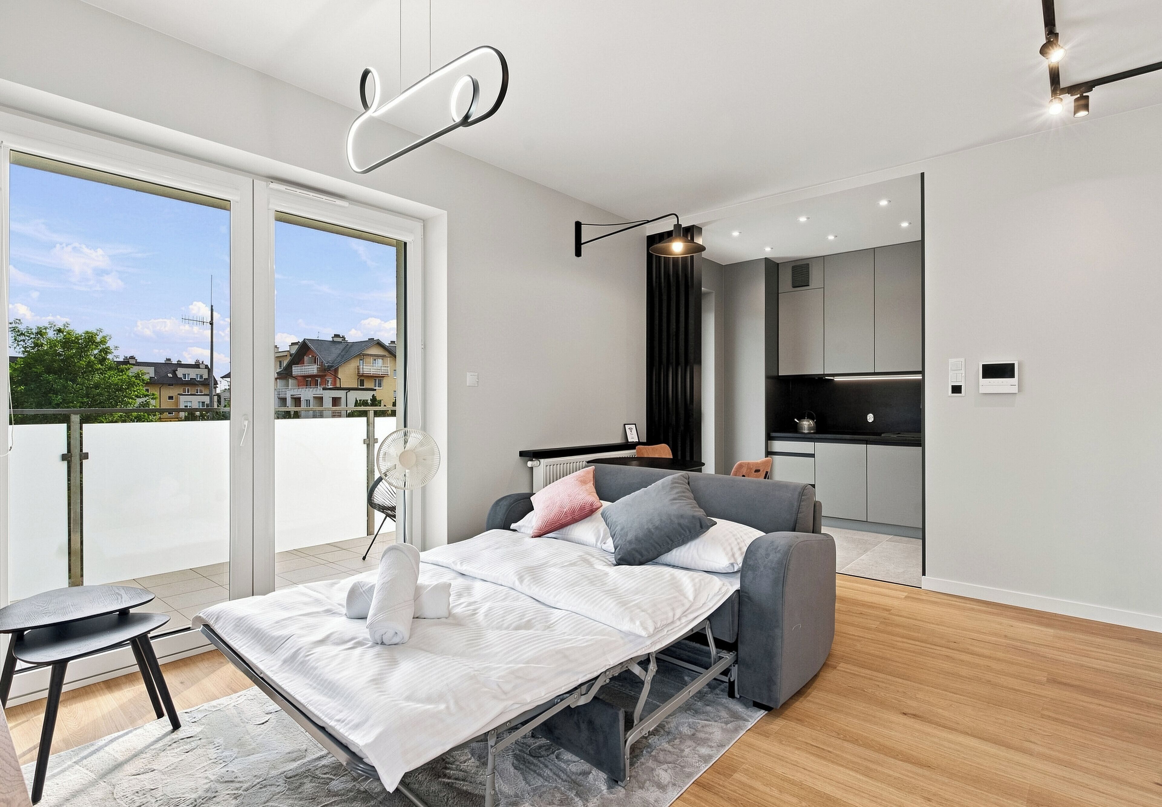 Quarto moderno com cama, mesa de cabeceira e vista para o exterior.