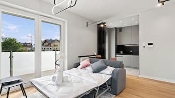 Quarto moderno com cama, mesa de cabeceira e vista para o exterior.
