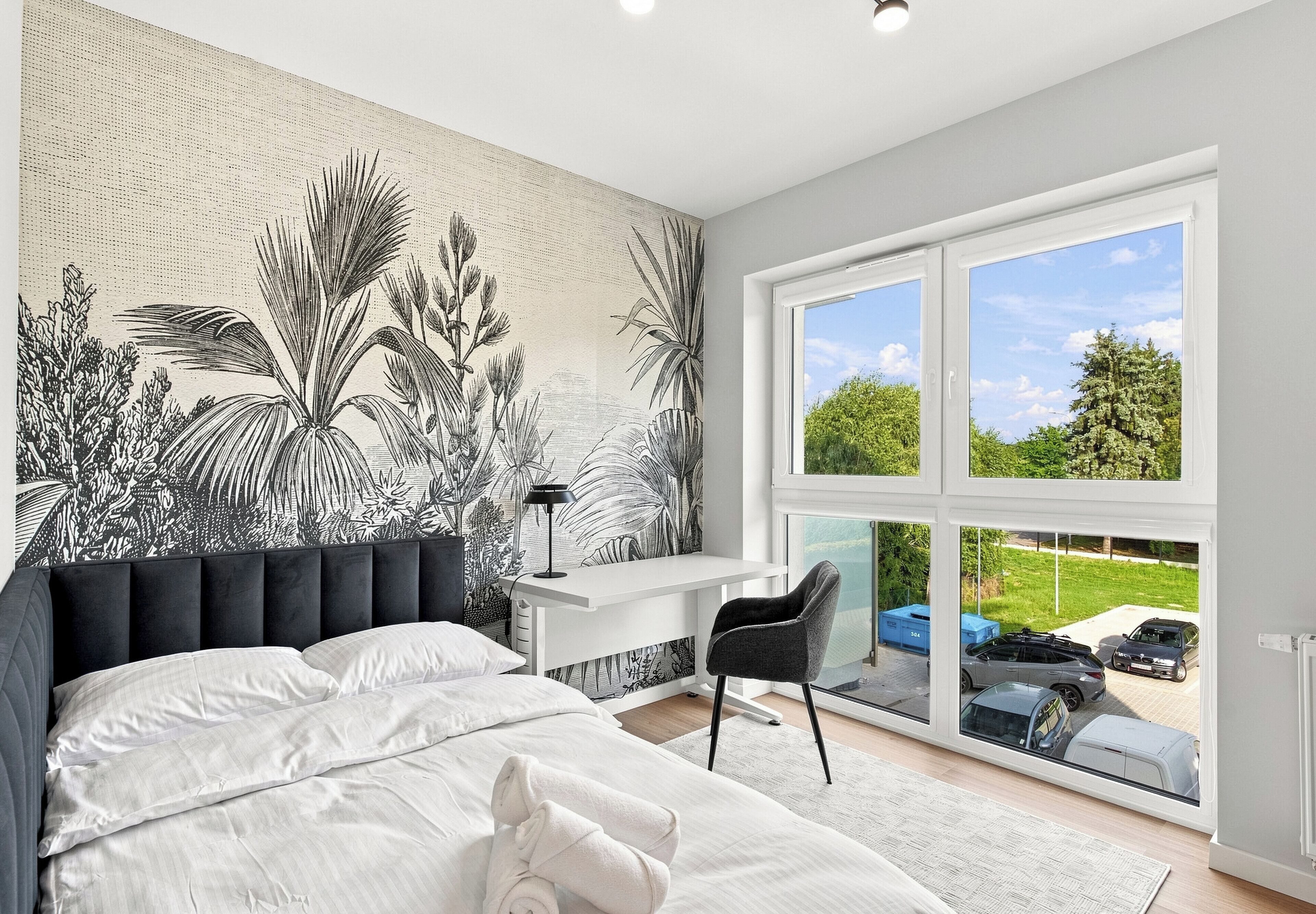 Une chambre avec un grand lit, un bureau et une chaise. Il y a une fenêtre donnant sur l’extérieur.