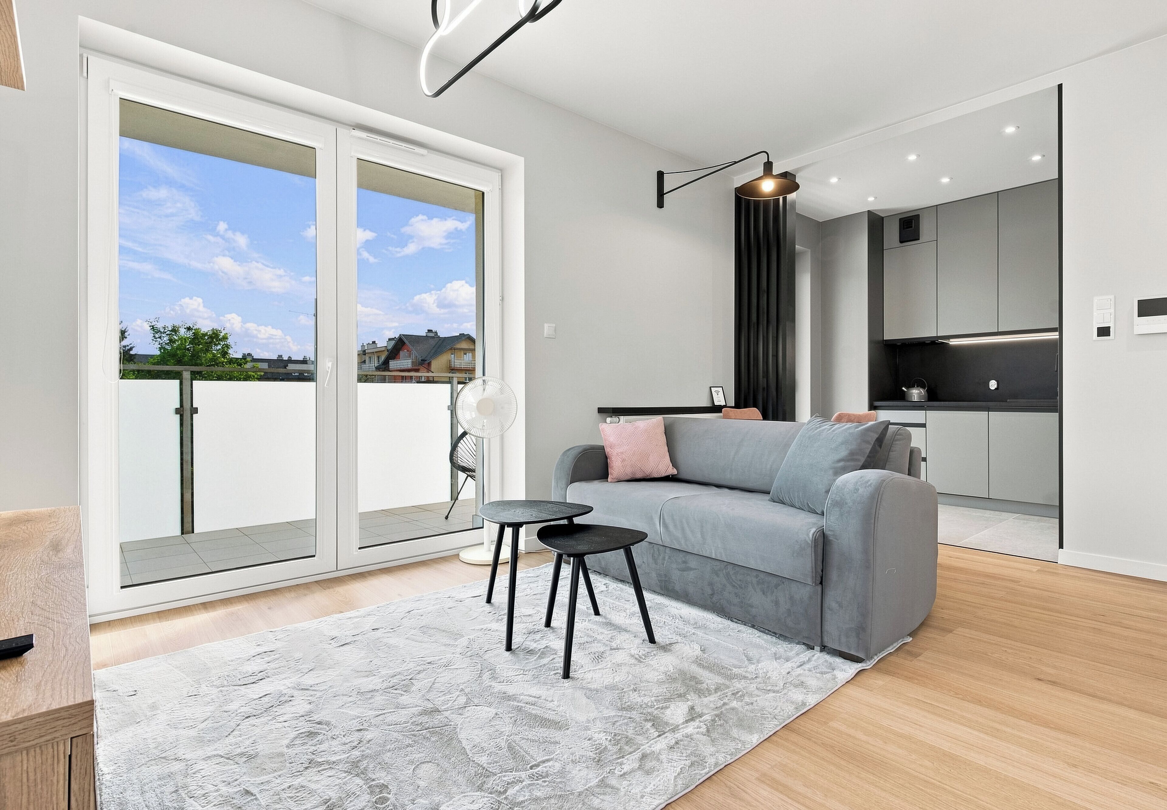 Un salon moderne avec un canapé gris, une petite table ronde et un tapis blanc.