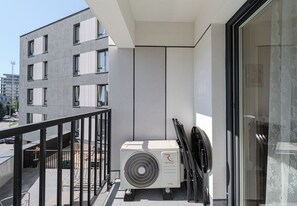 A balcony with a modern air conditioning unit, a glass door, and a view of a cityscape. - Podpromie Modern Apartment (Rzeszów)
