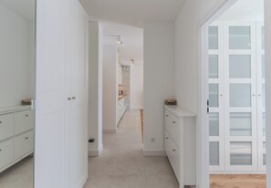 Ein Flur mit weißen Schränken, einer Küchenzeile und einer Tür mit satinierten Glasscheiben.