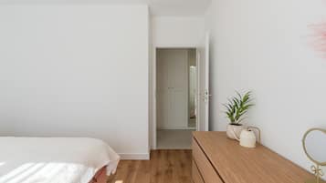Un dormitorio con cama, cómoda de madera, planta en maceta y espejo.