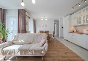 Ein modernes Wohnzimmer mit Sofa, Esstisch und Küchenzeile.