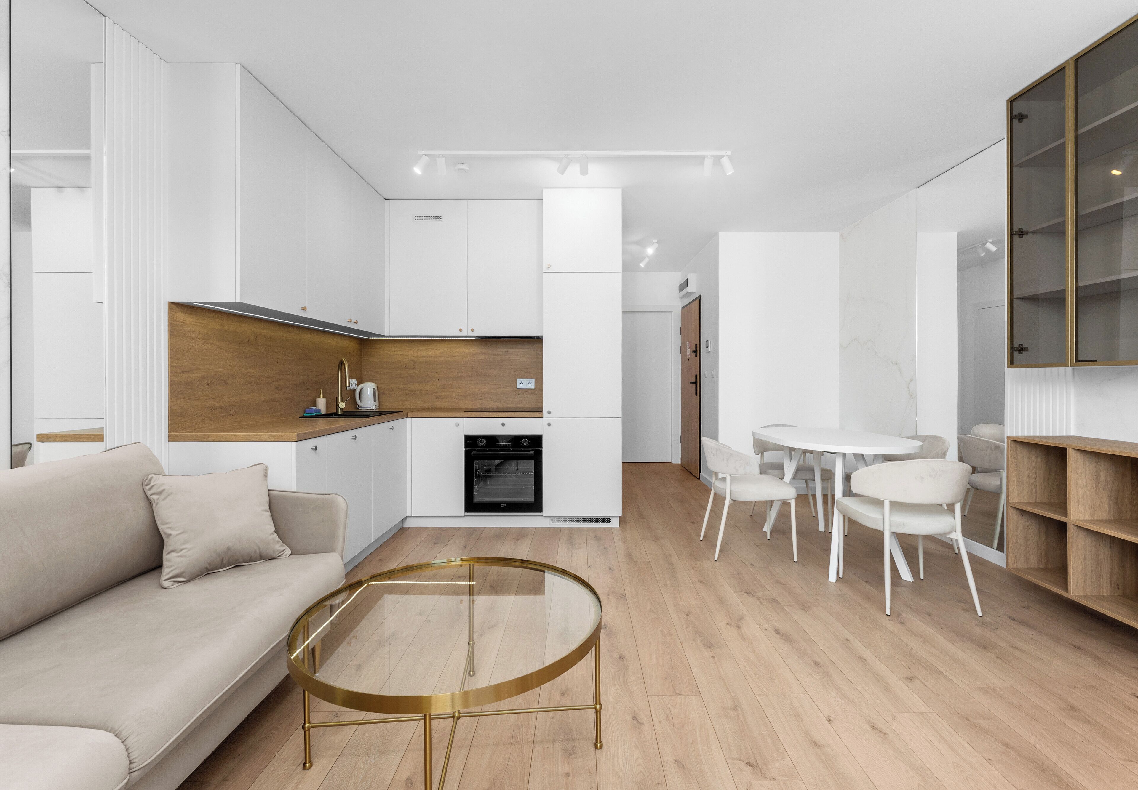 A modern living room with a sofa, a glass coffee table, and a dining area with chairs.