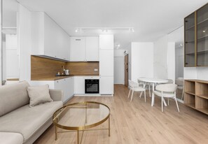 Un salon moderne avec un canapé, une table basse en verre et un coin repas avec des chaises.