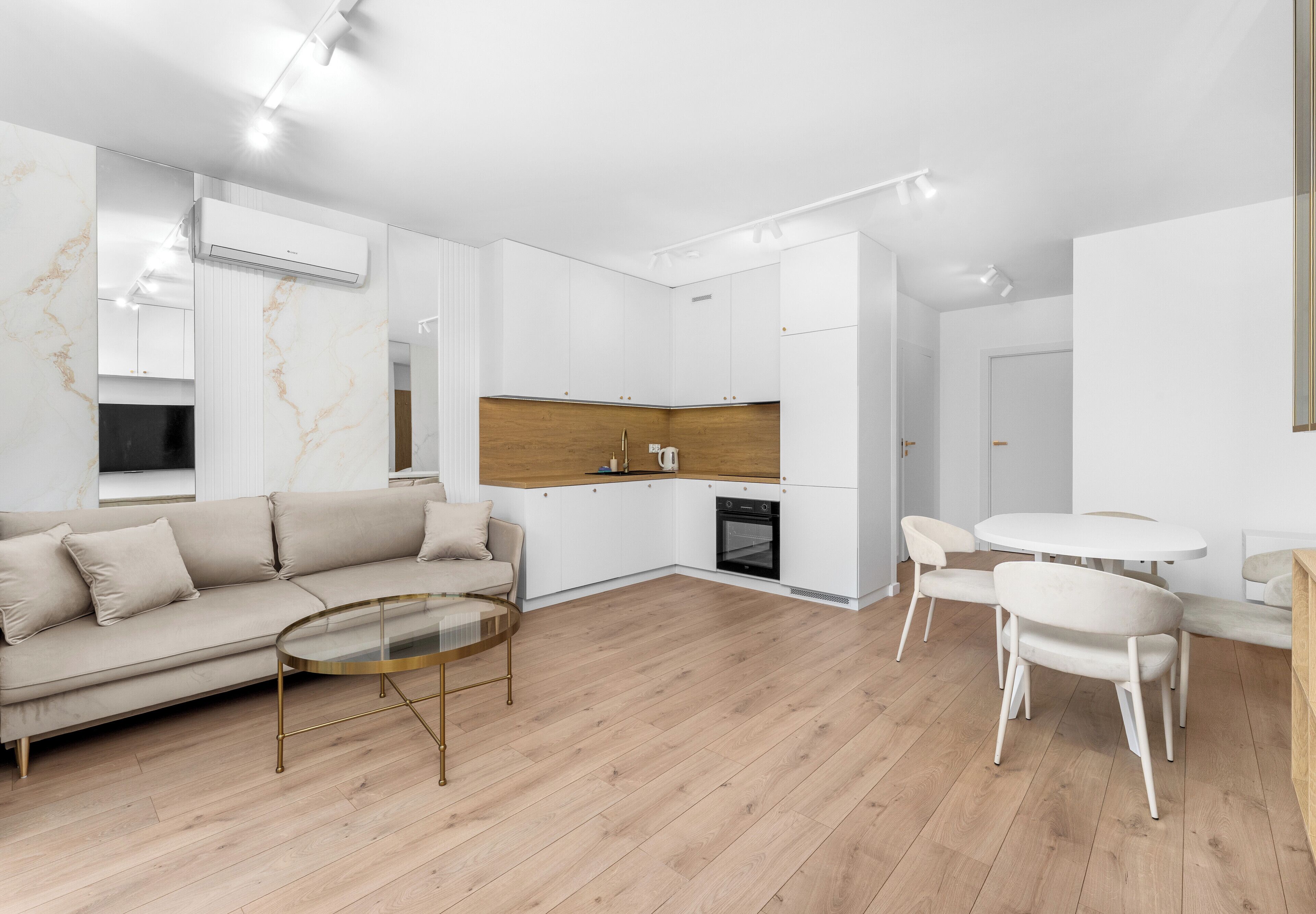 Un espace de vie moderne comprenant un canapé, une table basse, un coin repas, une cuisine et des appareils électroménagers intégrés.