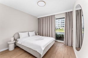 A modern hotel room with a bed, bedside table, and a large window with curtains. - Ciesielskiego Glamour Apartment (Kraków)