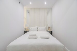 Ein Hotelzimmer mit einem großen Bett, zwei Nachttischen mit Lampen und einem Spiegel an der Wand.