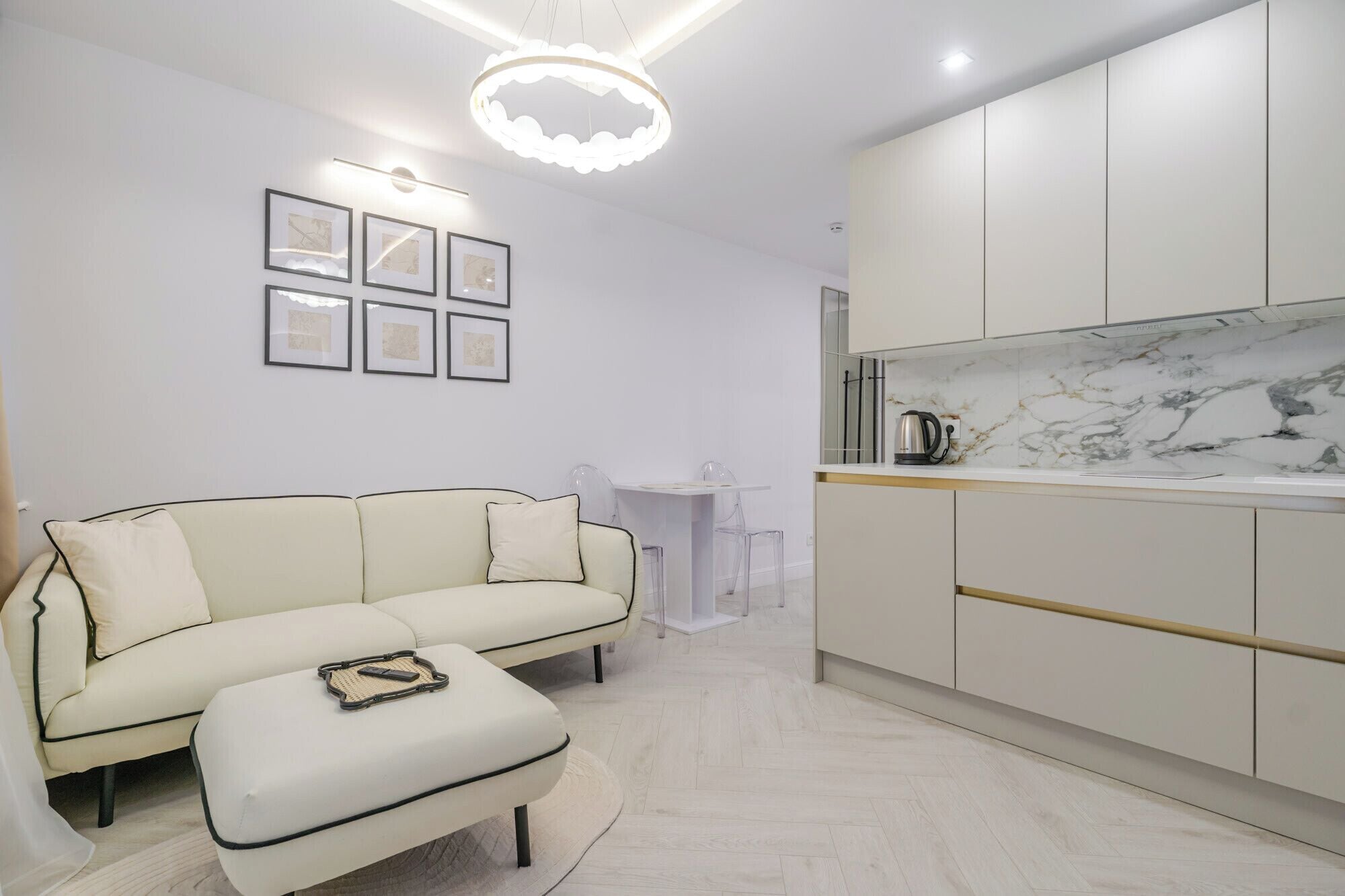 Una sala moderna con sofá, reposapiés y un comedor con mesa y sillas.