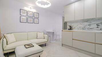 Una sala moderna con sofá, reposapiés y un comedor con mesa y sillas.