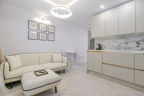 Ein modernes Wohnzimmer mit einer Couch, Hocker und einem Essbereich mit Tisch und Stühlen.