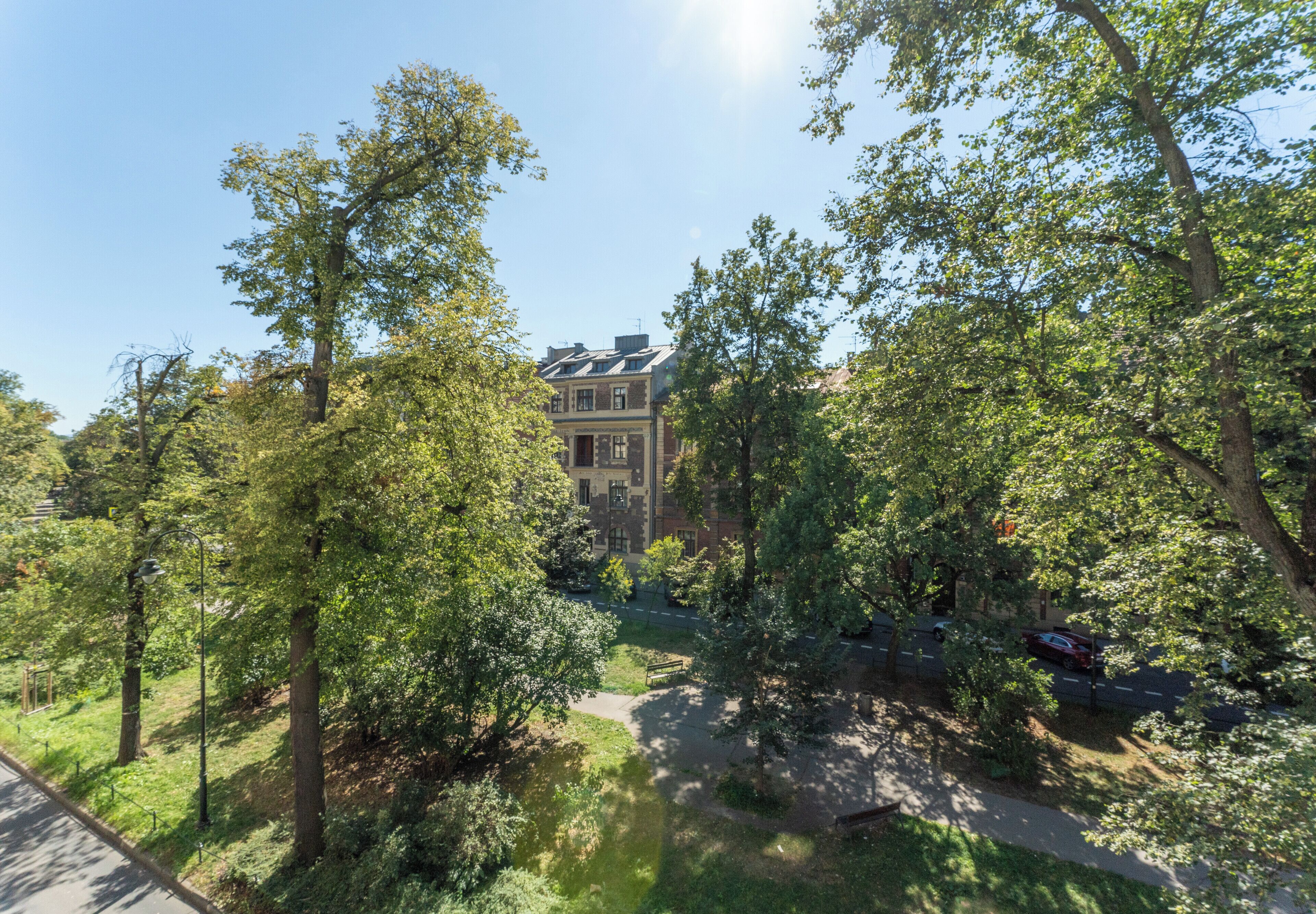 Une grande maison à deux étages, entourée d’une végétation luxuriante et d’arbres.