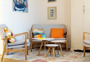 A cozy living room with a grey sofa, wooden chairs, a small round table, and colorful cushions. - Retoryka Old Town Colorful Studio (Kraków)