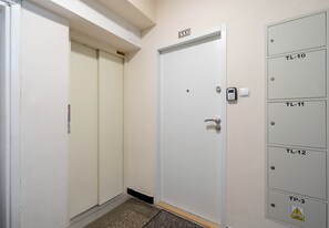 A hallway with a closed door, a set of lockers labeled with room numbers, and a doorbell. - Retoryka Old Town Colorful Studio (Kraków)